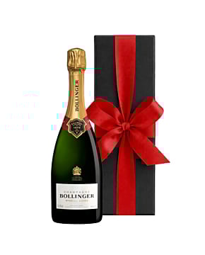 A bottle of Bollinger Special Cuvée Champagne standing next to a sleek black luxury gift box finished with a large, hand-tied red ribbon.