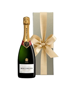 A bottle of Bollinger Special Cuvée Champagne standing next to an opulent gold luxury gift box finished with a large, hand-tied ribbon.