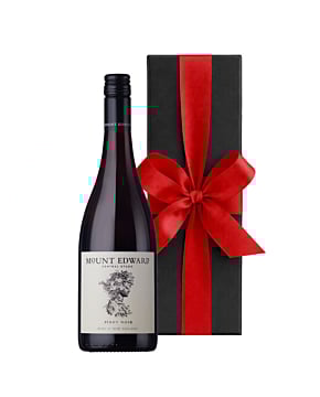 A bottle of Mount Edward Pinot Noir standing next to a sleek black luxury gift box finished with a large, hand-tied ribbon.