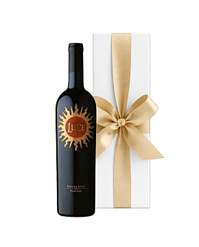 A bottle of Tenuta Luce 2020 Super Tuscan wine showing the golden sunburst label, presented in a signature white gift box with a large, hand-tied ribbon.