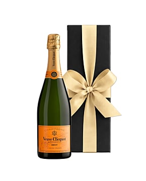 A bottle of Veuve Clicquot Yellow Label Brut Champagne standing next to a sleek black luxury gift box finished with a large, hand-tied ribbon.